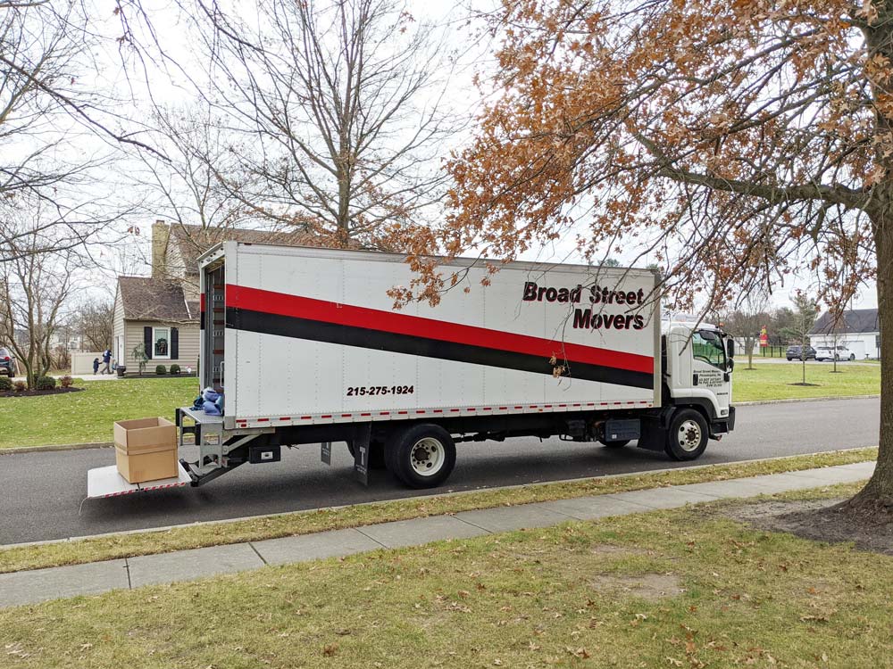 Broad Street Movers moving truck shown with the truck-bed ramp lowered and parked in front of residential home located around the Philly area