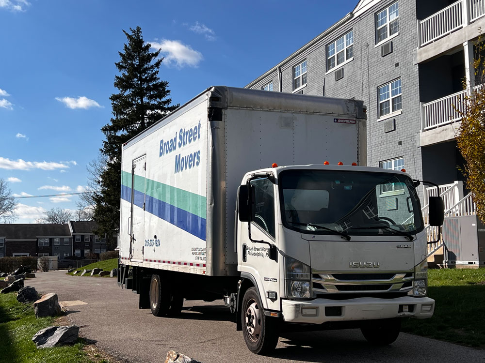 A Broad Street Movers moving truck parked outside of a three-story apartment building located around the Philly area