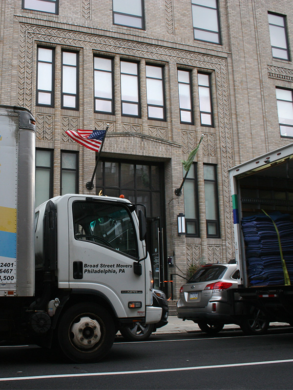 Broad Street Movers trucks parked in street outside nice corporate building in Philly