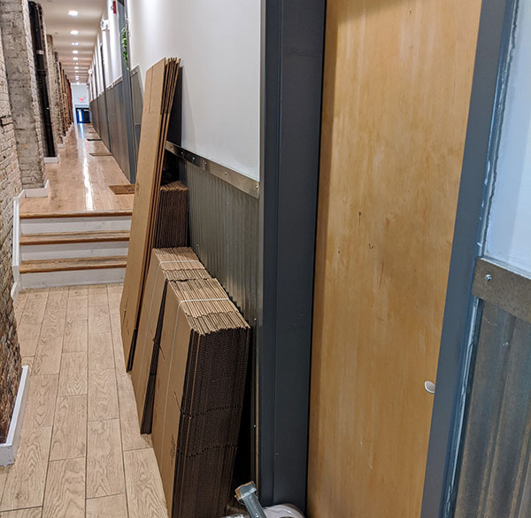 Stacks of new, unfolded packing boxes are lined up in a long corridor of a modern office building as another local office move begins in the Philly area