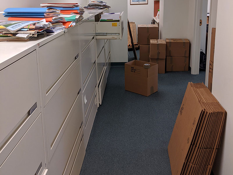 Several office cabinets with folders and paperwork on top during the packing process for an upcoming corporate office move